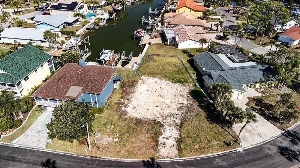 An aerial view shows a vacant waterfront lot situated between two existing residential homes — 4157 PERRY PLACE, NEW PORT RICHEY, FL