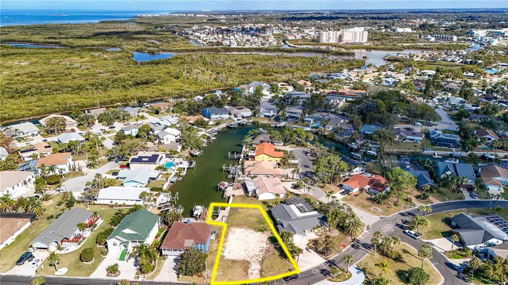 An aerial view shows a vacant residential lot outlined in yellow near a canal — 4157 PERRY PLACE, NEW PORT RICHEY, FL
