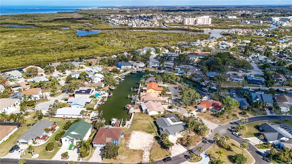 An aerial view shows residential homes situated along a canal leading to a coastal bay — 4157 PERRY PLACE, NEW PORT RICHEY, FL