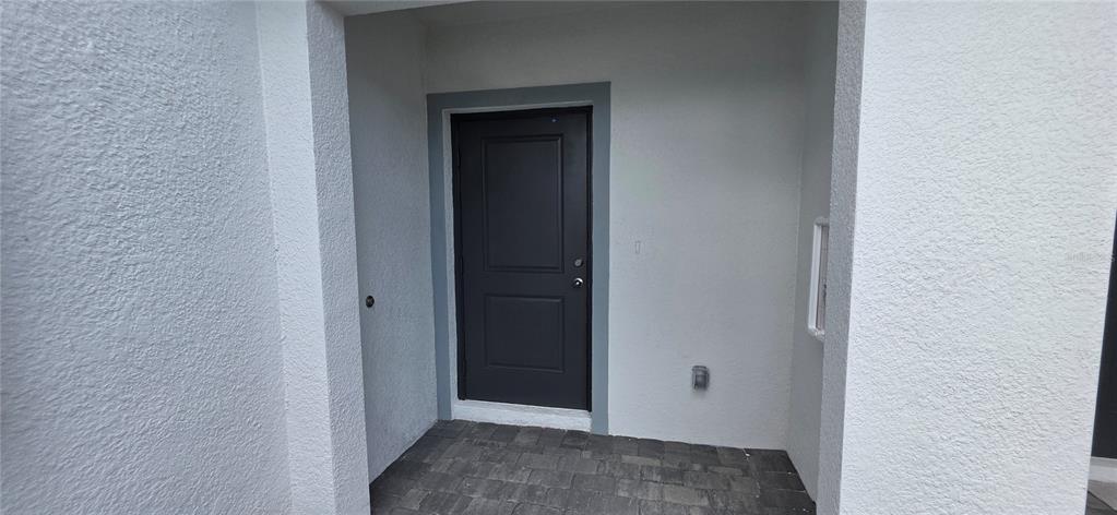 A dark gray front door is set within a recessed white stucco entryway with pavers — 14523 LILAC SKY TERRACE, BRADENTON, FL