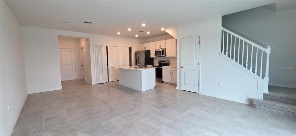 An open-concept kitchen features white cabinetry, stainless steel appliances, and a central island — 14523 LILAC SKY TERRACE, BRADENTON, FL
