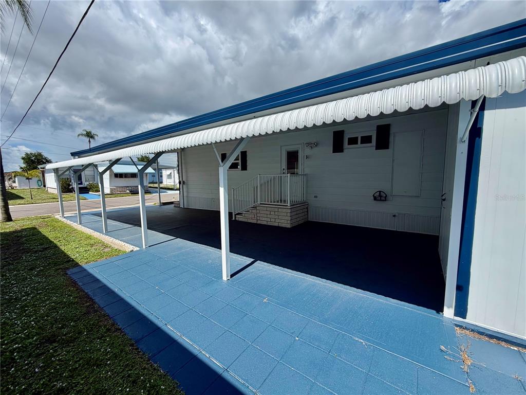 A mobile home exterior features a large blue-painted concrete carport and a covered entrance — 34548 VIOLET DRIVE N, PINELLAS PARK, FL