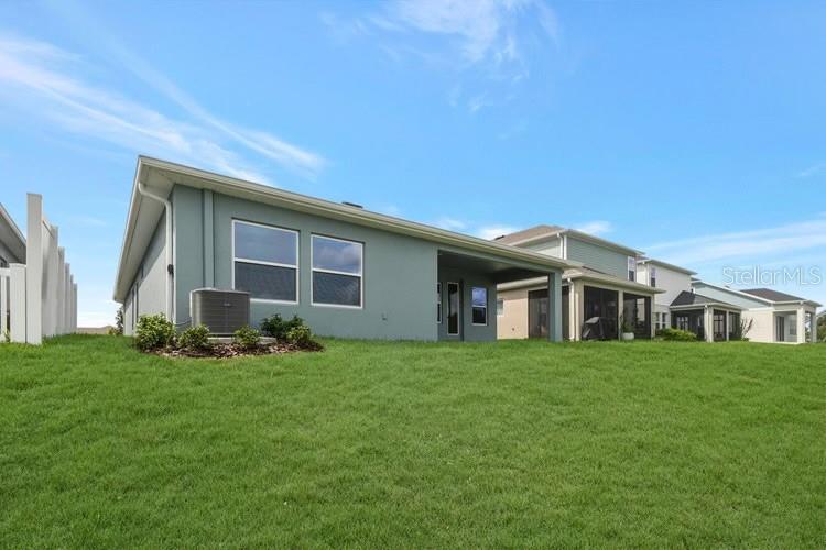 The rear exterior of a single-story house features a covered patio and an air conditioning unit — 11865 MILE MARSH DRIVE, RIVERVIEW, FL