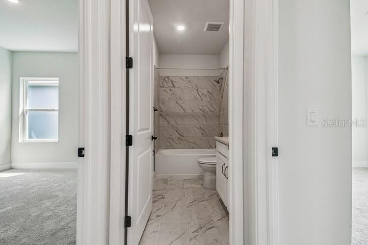 A bathroom with a marble-tiled tub surround and floor is visible through an open doorway — 11865 MILE MARSH DRIVE, RIVERVIEW, FL