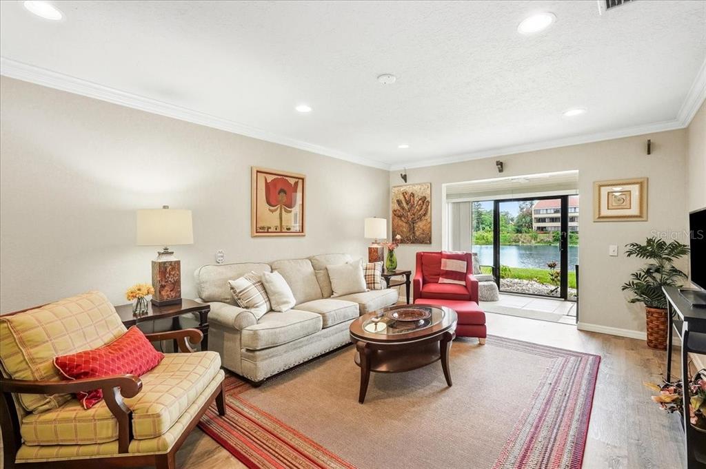 A living room features a sofa, armchairs, a coffee table, and sliding doors overlooking water — 4540 BEE RIDGE ROAD UNIT Villa 1, SARASOTA, FL