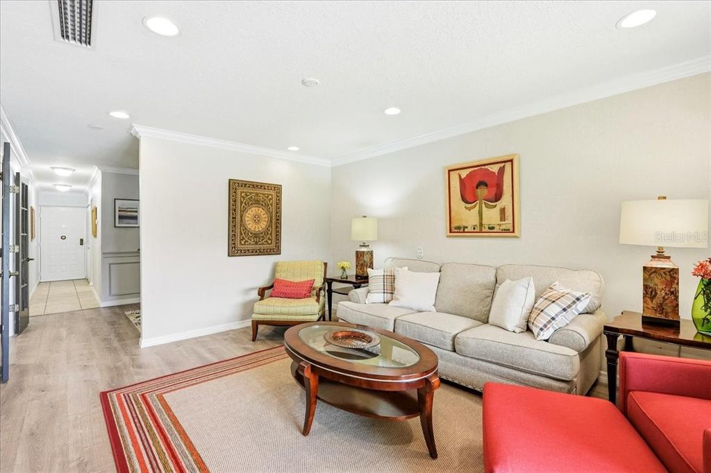 A living room features a beige sofa, a red armchair, and a glass-topped coffee table — 4540 BEE RIDGE ROAD UNIT Villa 1, SARASOTA, FL