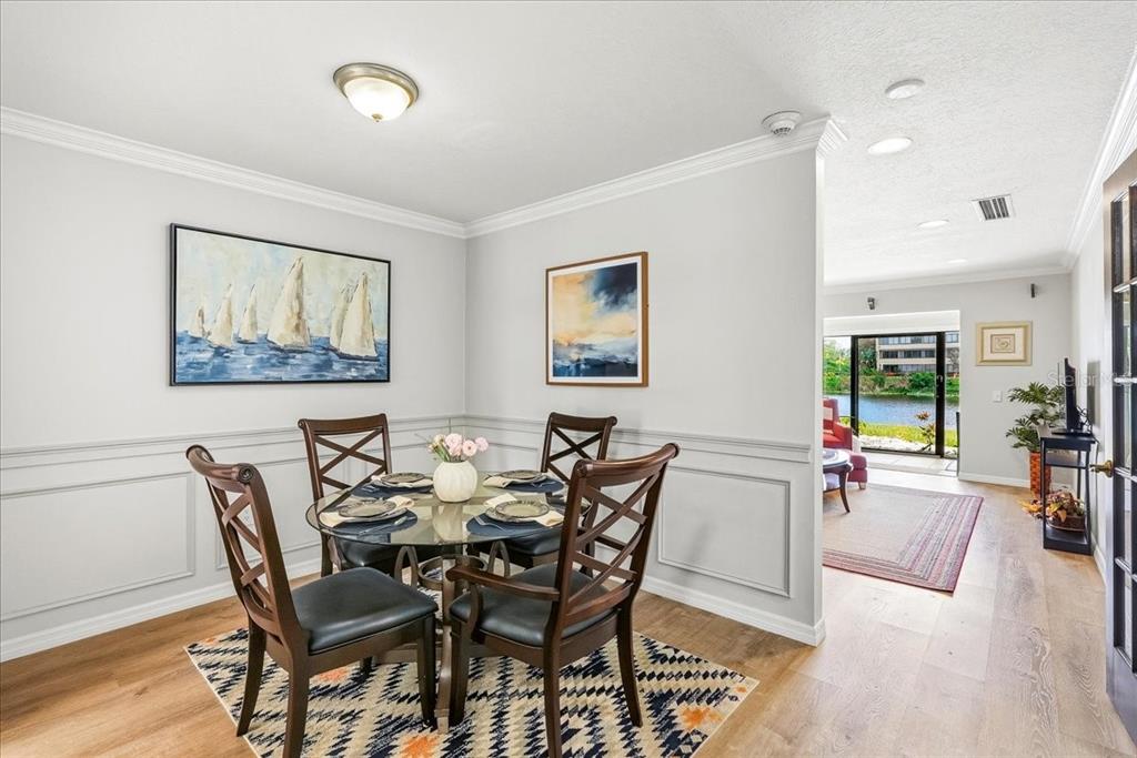A dining area with a glass table, four chairs, and wainscoting, overlooking a waterfront view — 4540 BEE RIDGE ROAD UNIT Villa 1, SARASOTA, FL