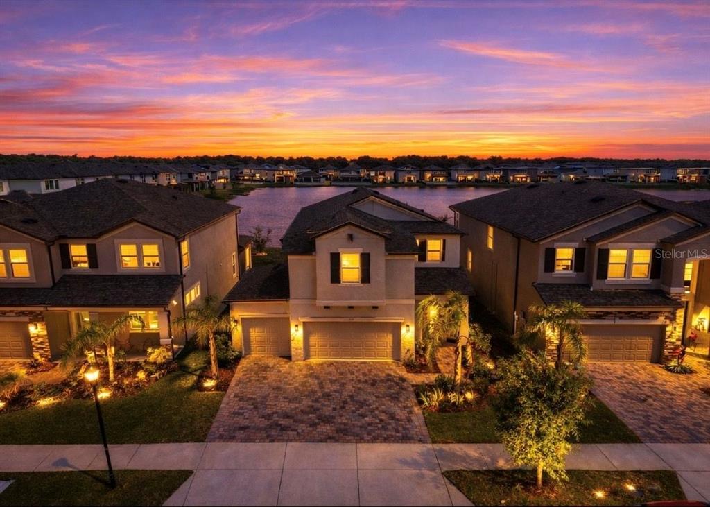 An aerial view of three suburban houses at sunset facing a lake — 3139 MARINE GRASS DRIVE, WIMAUMA, FL