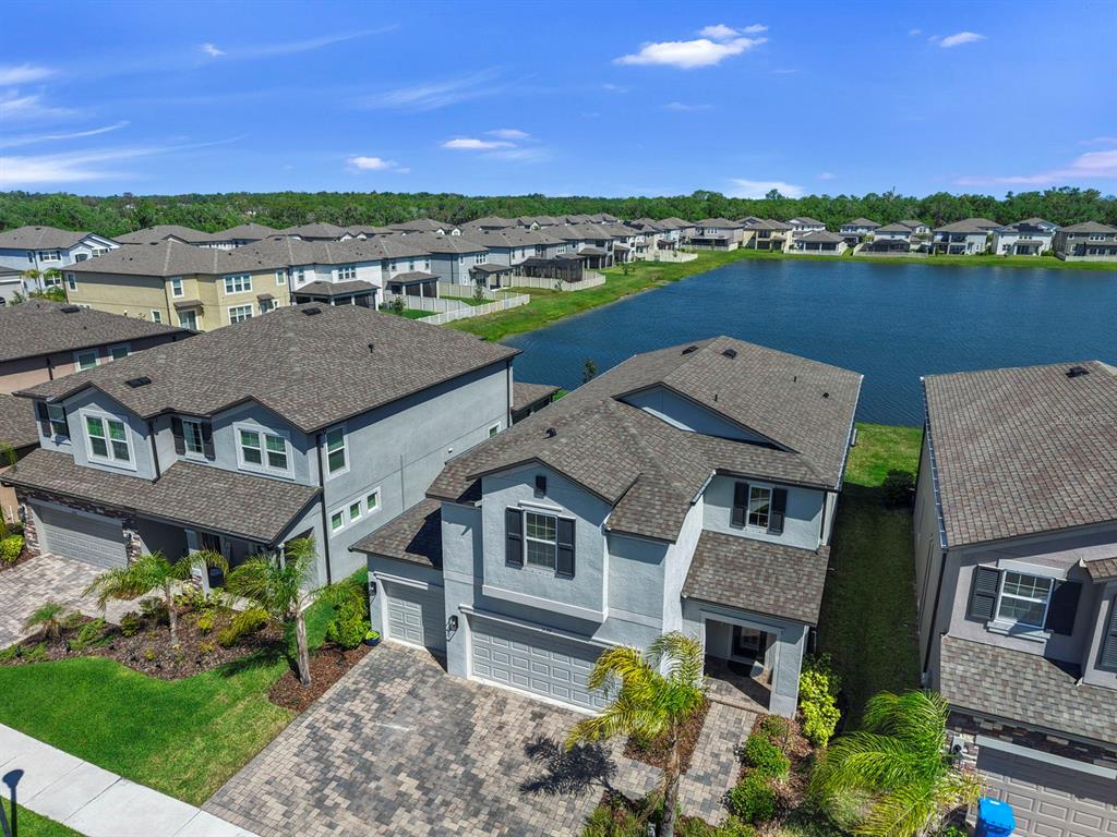 An aerial view shows suburban houses with gray roofs and driveways near a large pond — 3139 MARINE GRASS DRIVE, WIMAUMA, FL
