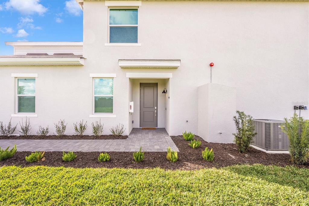 A light-colored two-story building exterior features a gray front door and a paved walkway — 17775 BORACAY COURT UNIT 102, VENICE, FL