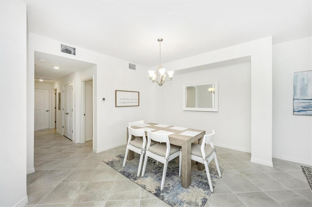 A dining area features a wooden table with four chairs on a patterned area rug — 17775 BORACAY COURT UNIT 102, VENICE, FL