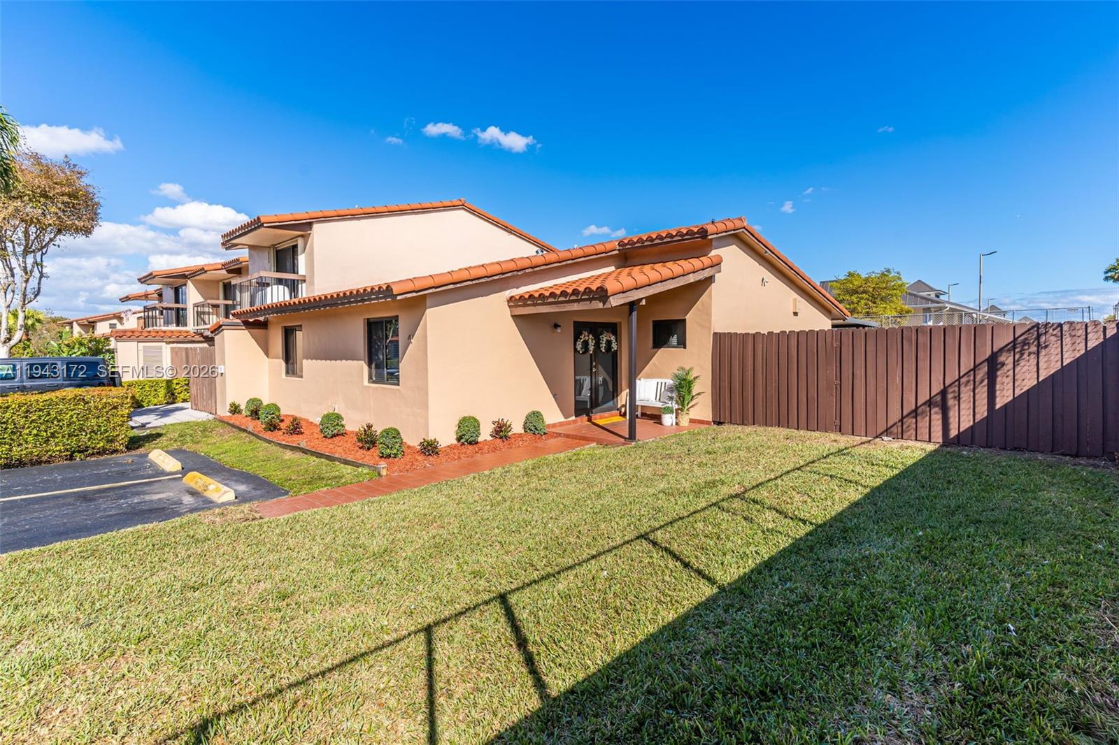 A tan, two-story townhouse with a tile roof, small front yard, and brown privacy fence — 3815 SW 82nd Ave # 41, Miami FL 33155, MIAMI, FL