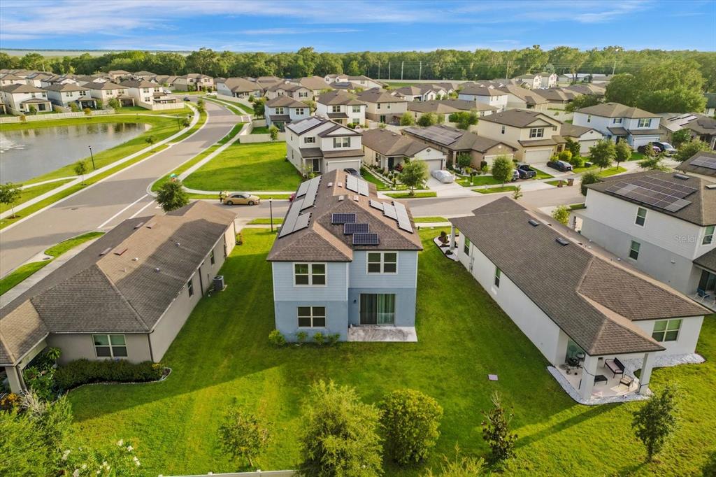 An aerial view shows a two-story house with solar panels surrounded by a suburban neighborhood — 3504 SOUTHERN CROSS LOOP, KISSIMMEE, FL