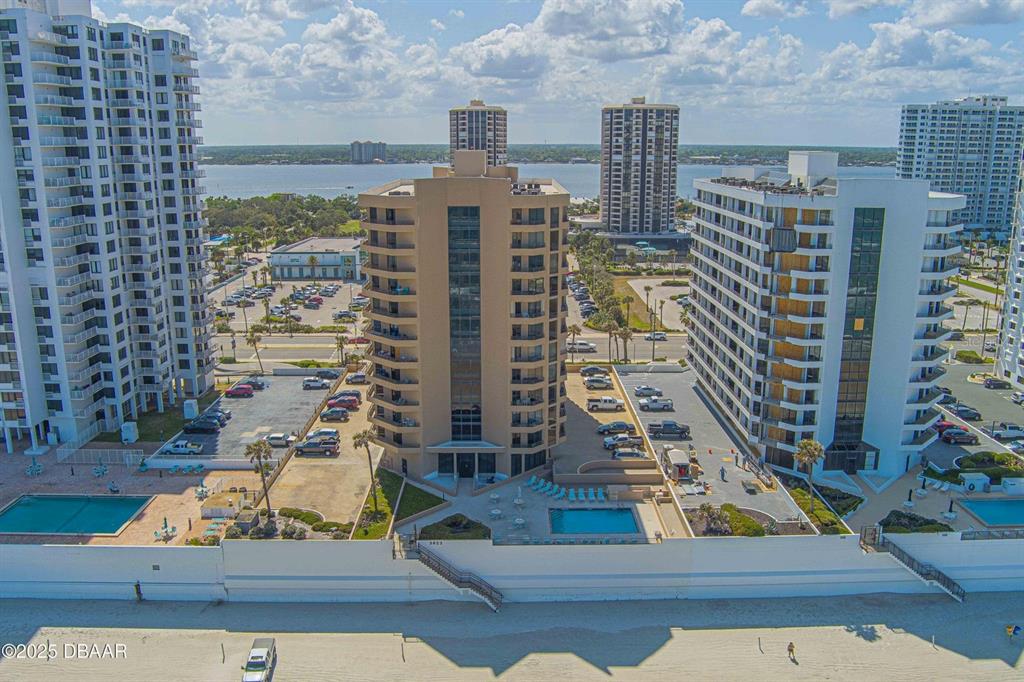 An aerial view shows several high-rise residential buildings situated along a sandy beach — 3023 S ATLANTIC AVENUE UNIT 8010, DAYTONA BEACH, FL