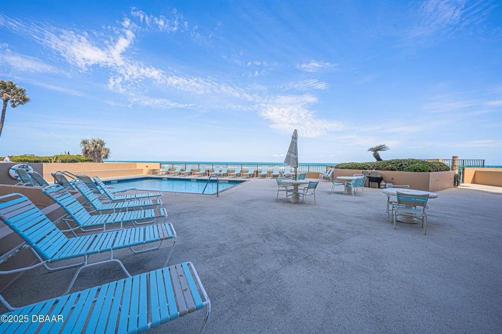 An outdoor swimming pool area features lounge chairs, tables, and a view of the ocean — 3023 S ATLANTIC AVENUE UNIT 8010, DAYTONA BEACH, FL