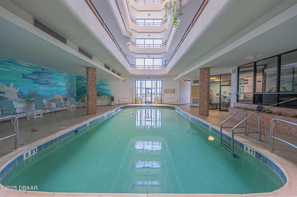 An indoor swimming pool is surrounded by a tiled deck, a mural, and multi-story balconies — 3023 S ATLANTIC AVENUE UNIT 8010, DAYTONA BEACH, FL