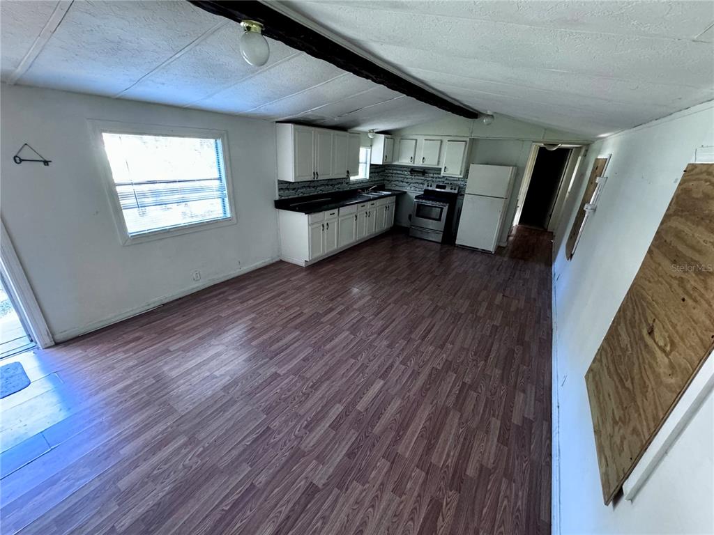 A kitchen with white cabinets, dark countertops, and wood-look flooring in an open-concept space — 13330 SW 9TH LANE, OCALA, FL