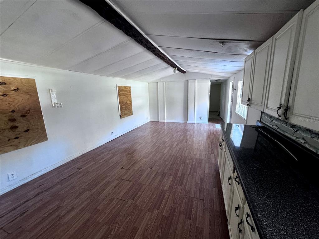 An interior view of a kitchen and living area with wood-look flooring and white walls — 13330 SW 9TH LANE, OCALA, FL