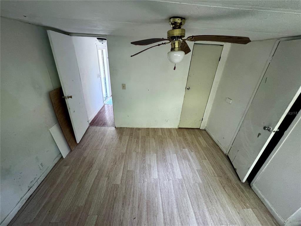 A room with light wood-look flooring, a ceiling fan, and multiple white doors — 13330 SW 9TH LANE, OCALA, FL