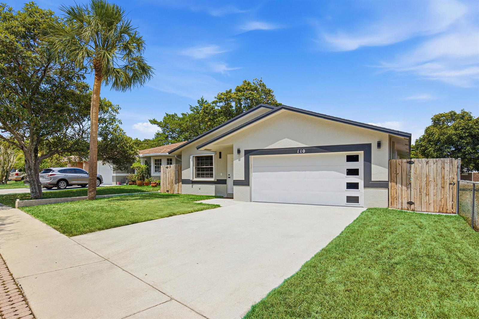 A single-story house with a white garage door, gray trim, and a concrete driveway — 110 NW 6th Avenue, Dania Beach FL 33004, DANIA BEACH, FL