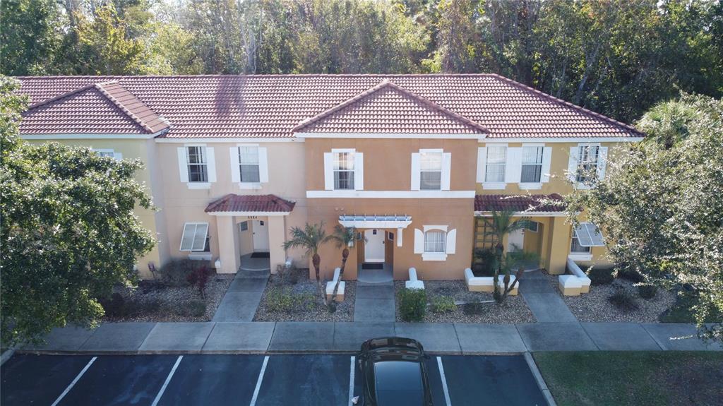 An exterior view of a two-story townhouse complex with a parking lot in front — 1115 PARK RIDGE CIRCLE, KISSIMMEE, FL