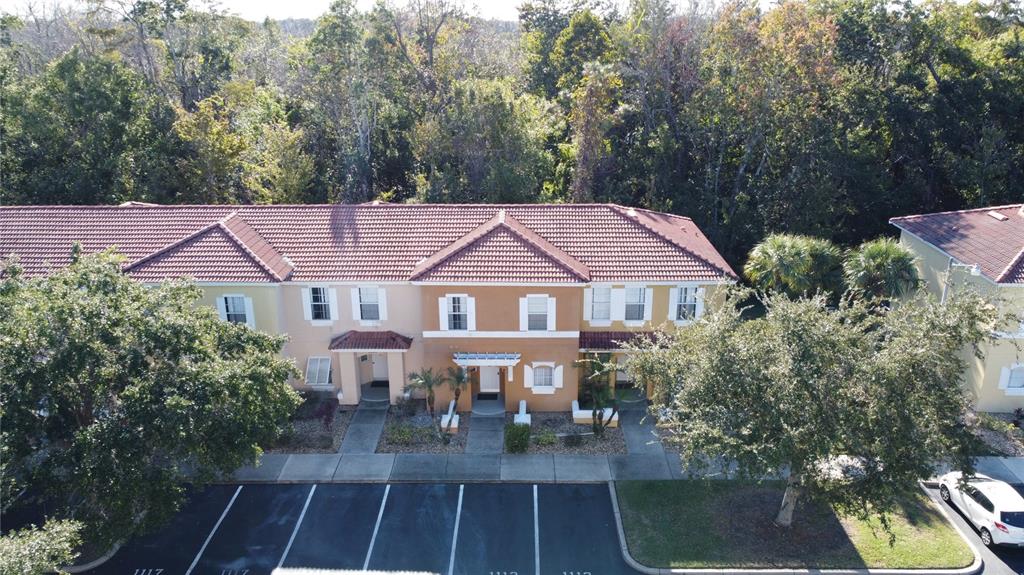 An aerial view of a multi-unit townhouse building with a tiled roof and parking lot — 1115 PARK RIDGE CIRCLE, KISSIMMEE, FL