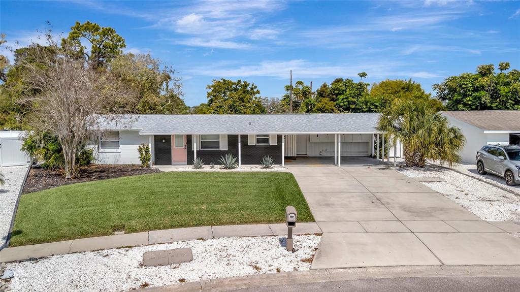 A single-story house with a white exterior, a black accent wall, and a concrete driveway — 6426 COLONIAL DRIVE, SARASOTA, FL