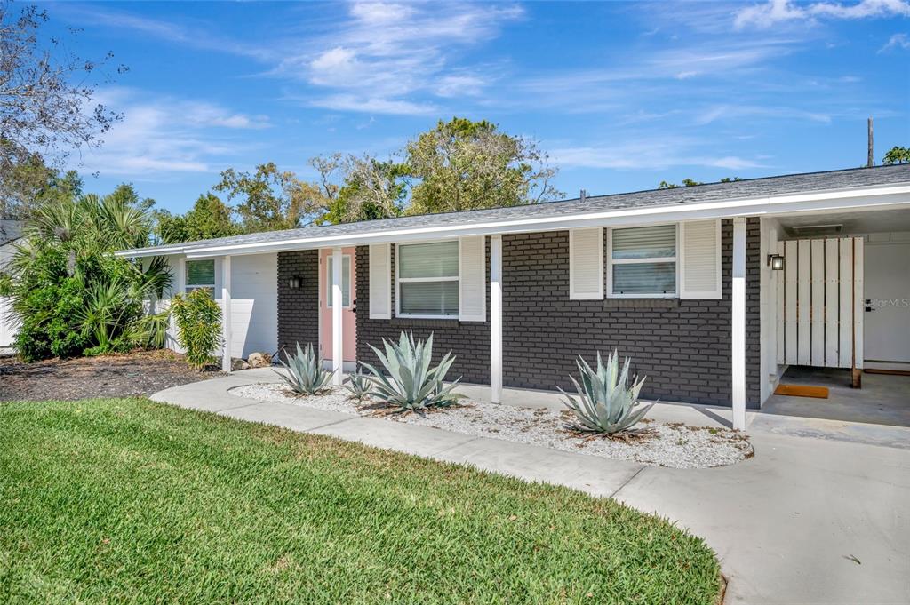 A single-story house with dark brick siding, white trim, and a light pink front door — 6426 COLONIAL DRIVE, SARASOTA, FL