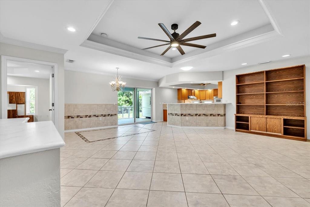 An open-concept living and dining area features tile flooring, a tray ceiling, and built-in shelving — 23230 STELLING AVENUE, PORT CHARLOTTE, FL