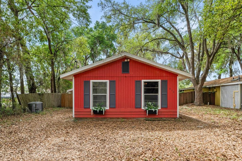 A small, red-sided house with two windows, dark shutters, and flower boxes sits outdoors — 615 NW 24TH AVENUE, GAINESVILLE, FL