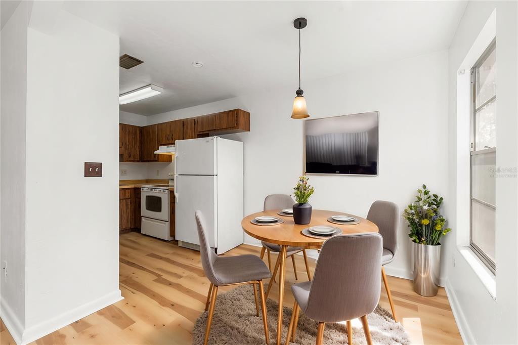 A dining area with a round wooden table and chairs sits adjacent to a kitchen — 615 NW 24TH AVENUE, GAINESVILLE, FL