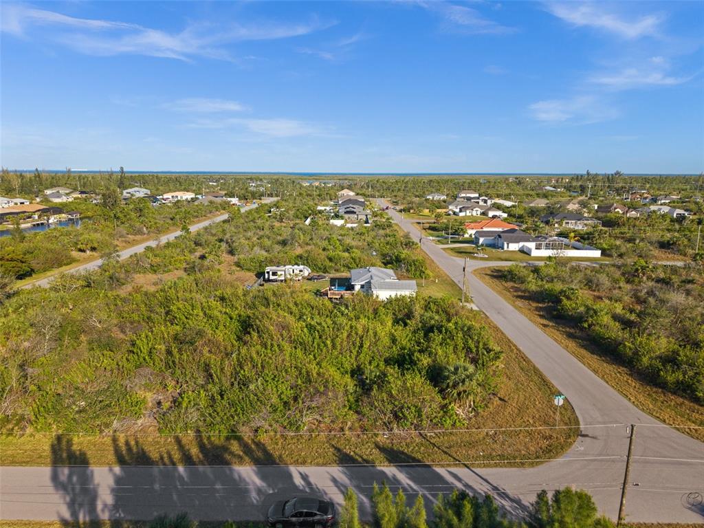 An aerial view shows a residential lot with dense vegetation, a house, and nearby roads — 10177 OWL HEAD CIRCLE, PORT CHARLOTTE, FL