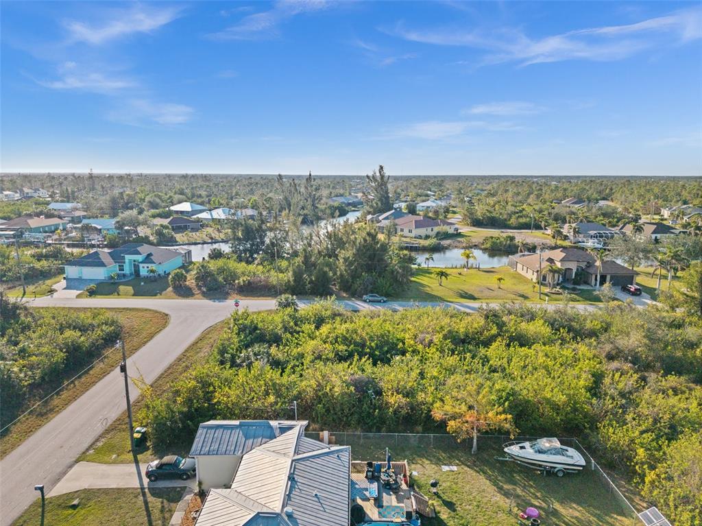 An aerial view shows a residential neighborhood with houses, a canal, and surrounding vegetation — 10177 OWL HEAD CIRCLE, PORT CHARLOTTE, FL