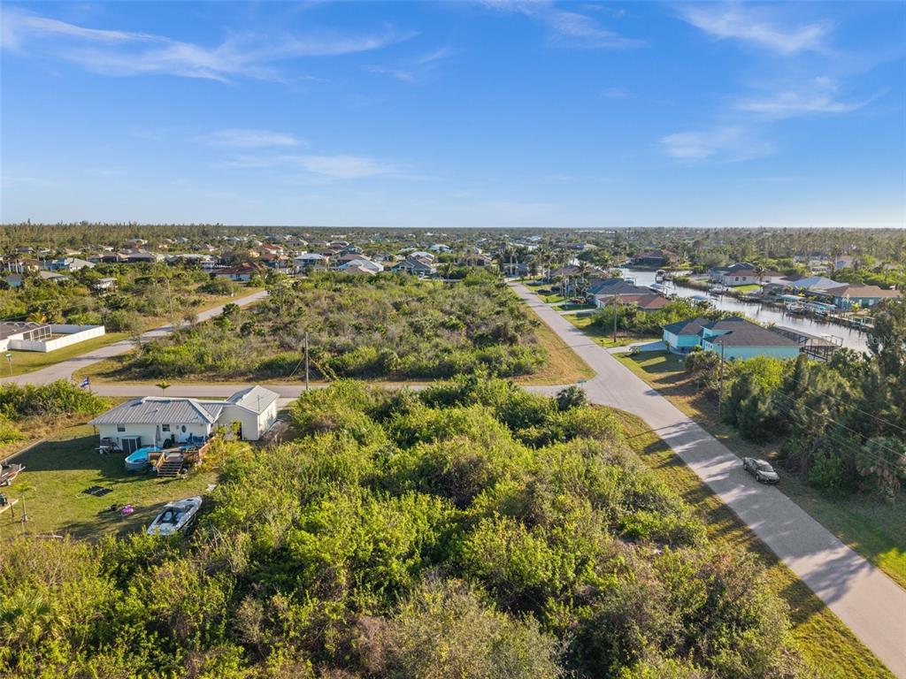 An aerial view shows a vacant, brush-covered lot next to a house with a pool — 10177 OWL HEAD CIRCLE, PORT CHARLOTTE, FL