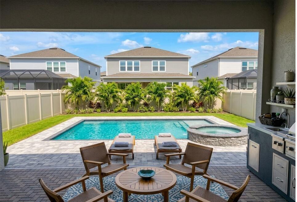 A covered patio overlooks a backyard with a swimming pool, hot tub, and lounge chairs — 13360 PANAMA BEACH COURT, ORLANDO, FL