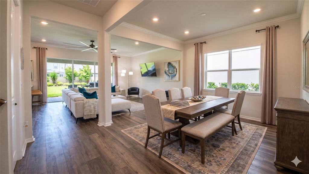An open-concept living and dining area features wood-look flooring, recessed lighting, and a sliding door — 13360 PANAMA BEACH COURT, ORLANDO, FL