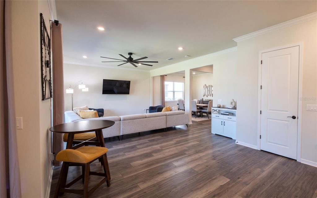 An open-concept living area features wood-look flooring, a sectional sofa, and a dining space — 13360 PANAMA BEACH COURT, ORLANDO, FL