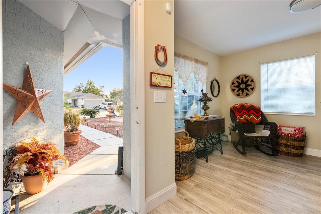A sunroom with wood-look flooring features a rocking chair, vintage sewing table, and exterior view — 47 WOOD ACRE LANE, PALM COAST, FL
