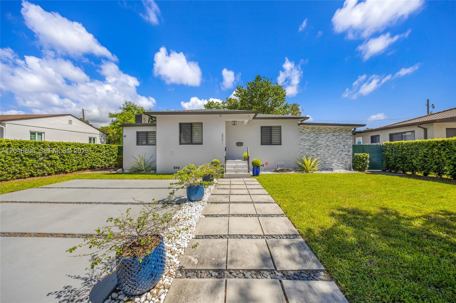 A single-story house with a white stucco facade, stone accent wall, and a paved walkway — 6541 SW 18th St, West Miami FL 33155, WEST MIAMI, FL
