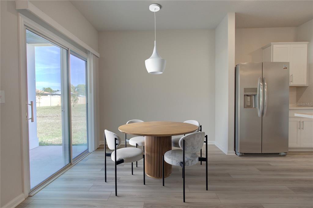 A dining area features a round wooden table, four chairs, and a sliding glass door — 10 FRENEAU LANE, PALM COAST, FL