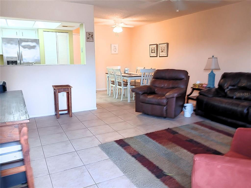 A living room with tile flooring, a dining area, and a kitchen pass-through window — 8150 BRADDOCK CIRCLE UNIT 3, PORT RICHEY, FL