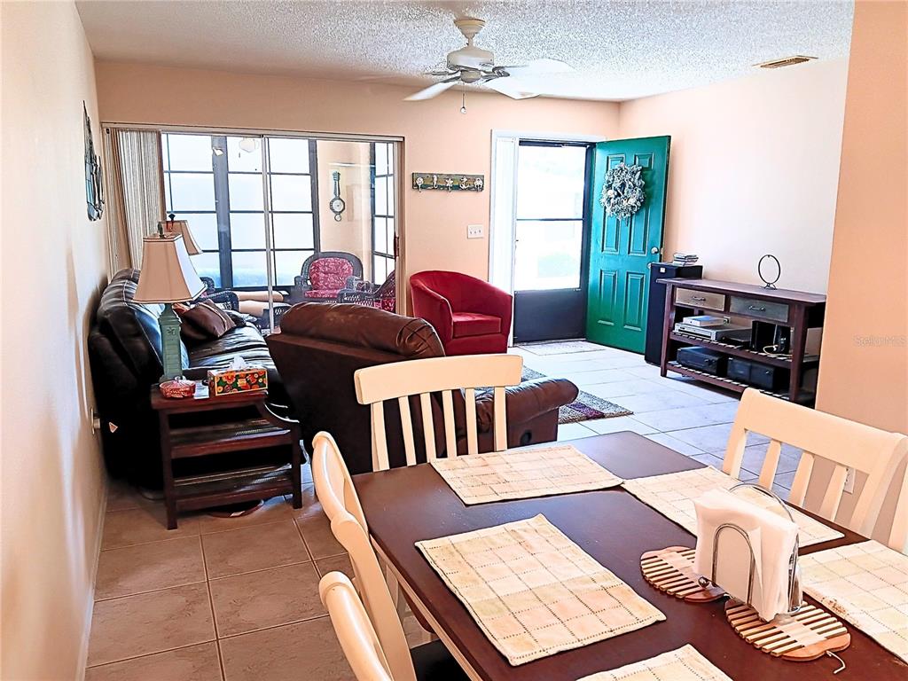 A living room and dining area feature tile flooring, a ceiling fan, and a green door — 8150 BRADDOCK CIRCLE UNIT 3, PORT RICHEY, FL