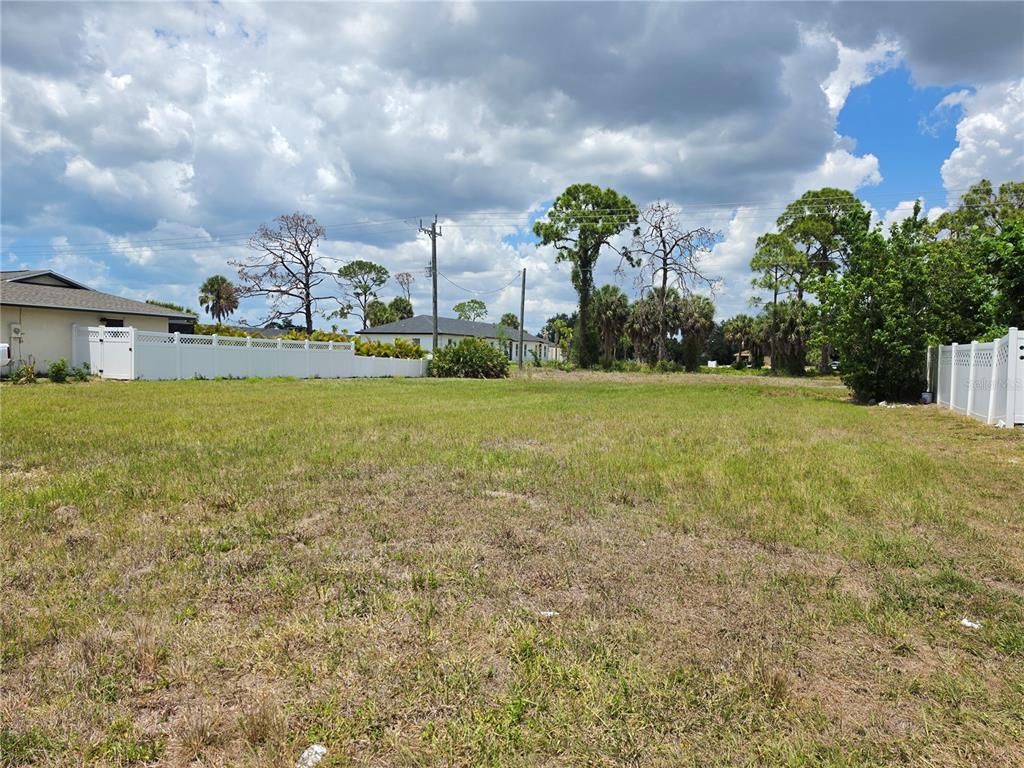 A vacant, grassy residential lot is bordered by white vinyl fencing and mature trees — 193 ANNAPOLIS LANE, ROTONDA WEST, FL