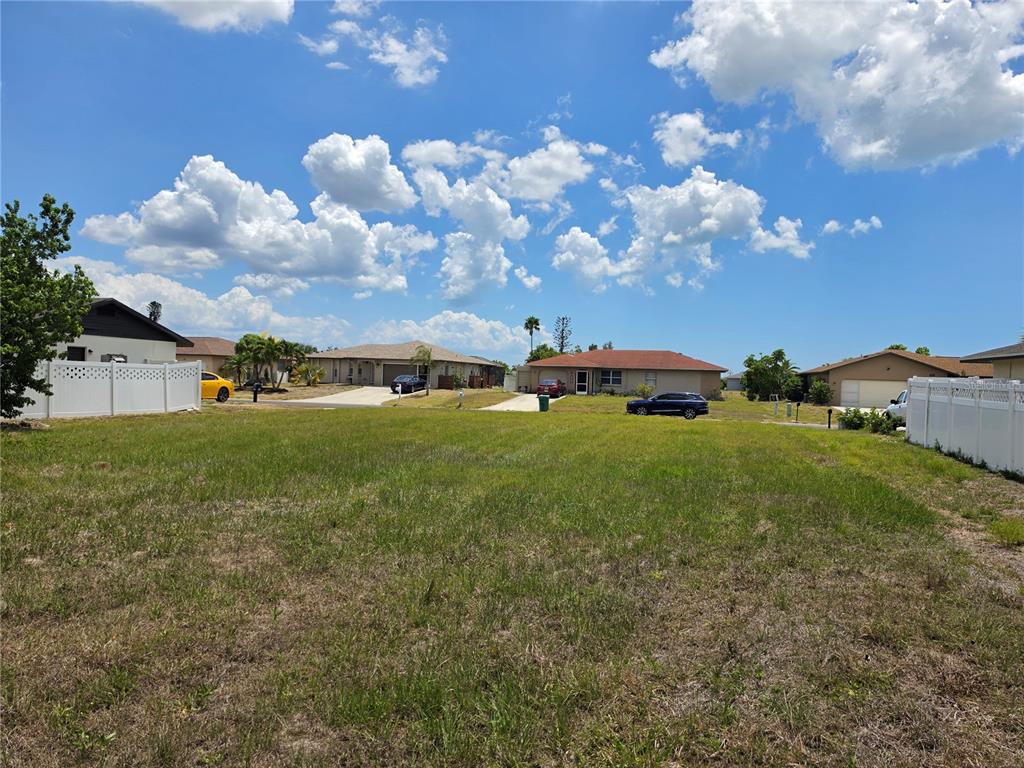 A vacant, grassy residential lot sits between two houses with white vinyl fences — 193 ANNAPOLIS LANE, ROTONDA WEST, FL