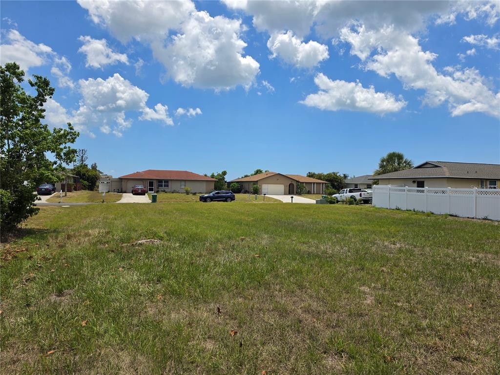 A vacant grassy lot sits in front of several single-story suburban houses under a blue sky — 193 ANNAPOLIS LANE, ROTONDA WEST, FL