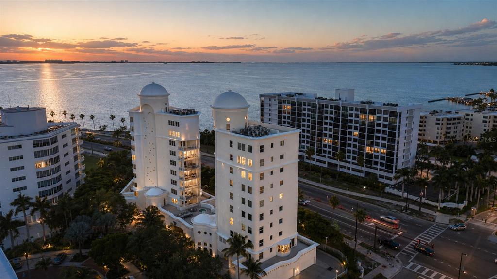 An aerial view of two white high-rise buildings overlooking a bay at sunset — 128 GOLDEN GATE POINT UNIT 202A, SARASOTA, FL