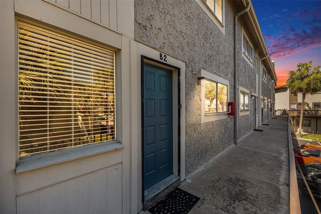 An exterior view of a multi-story apartment building with a concrete walkway and blue door — 6311 NEWTOWN CIRCLE UNIT 11B2, TAMPA, FL