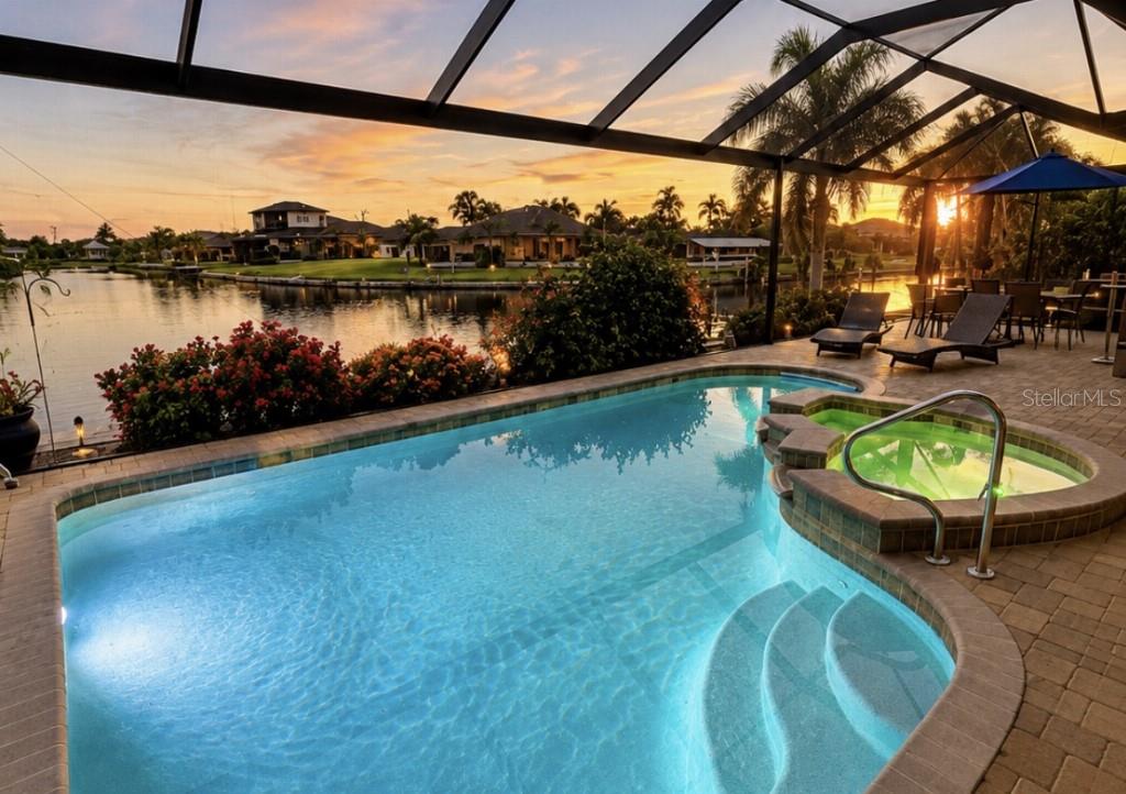 A screened-in patio features a swimming pool, a hot tub, and a view of a canal — 15452 ALSASK CIRCLE, PORT CHARLOTTE, FL