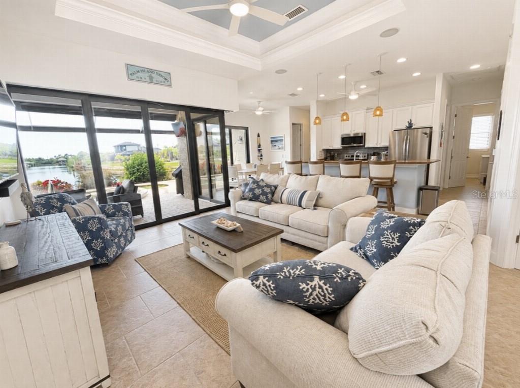 A living room with beige sofas, a coffee table, and large sliding doors overlooking water — 15452 ALSASK CIRCLE, PORT CHARLOTTE, FL
