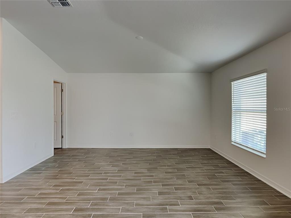 An empty room features white walls, light-colored wood-look tile flooring, and a single window — 301 PIAVE STREET, HAINES CITY, FL